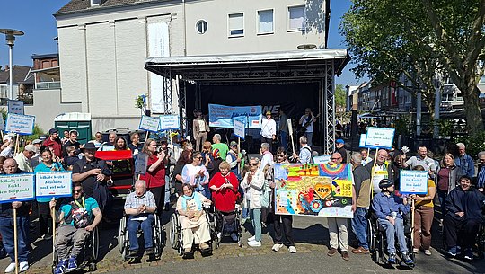 Gruppenbild: Menschen mit und ohne Behinderung vor einer Bühne.