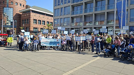 Gruppenbild: Menschen mit und ohne Behinderung halten Protestschilder hoch.