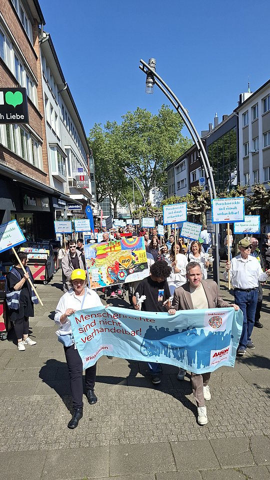 Demozug mit Protesttagbanner läuft durch Innenstadt.